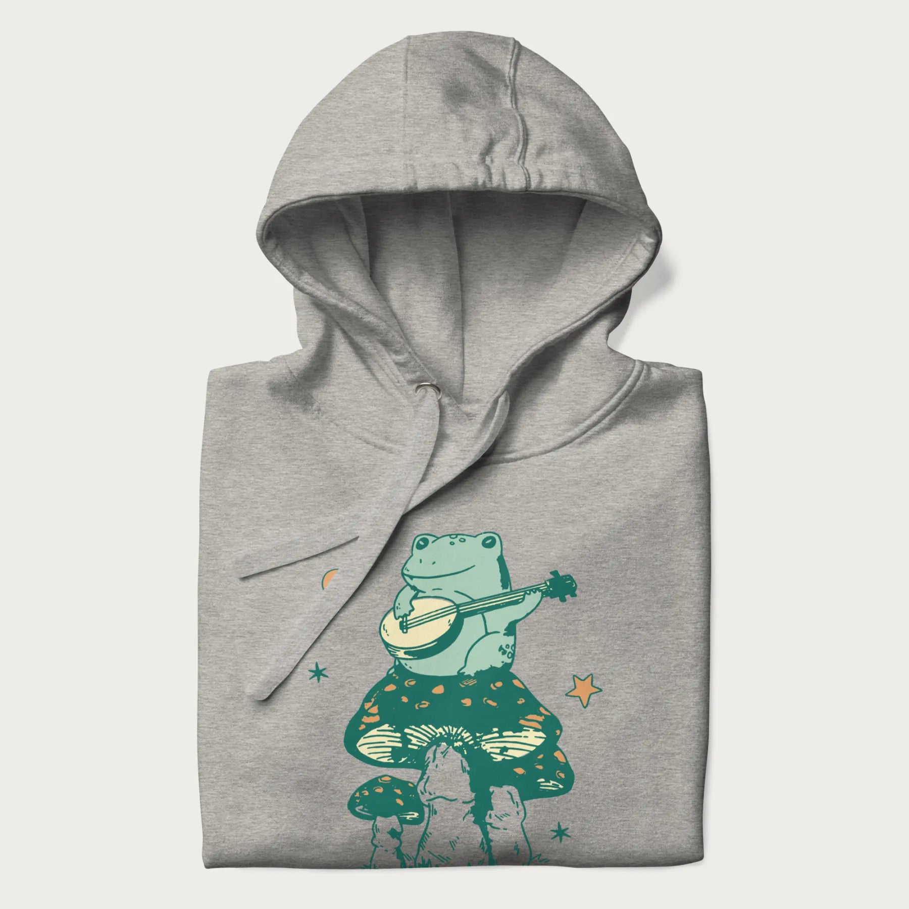 Folded light grey hoodie with graphic of a frog playing a banjo on a mushroom with stars and a crescent moon.