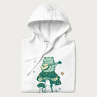 Folded white hoodie with graphic of a frog playing a banjo on a mushroom with stars and a crescent moon.