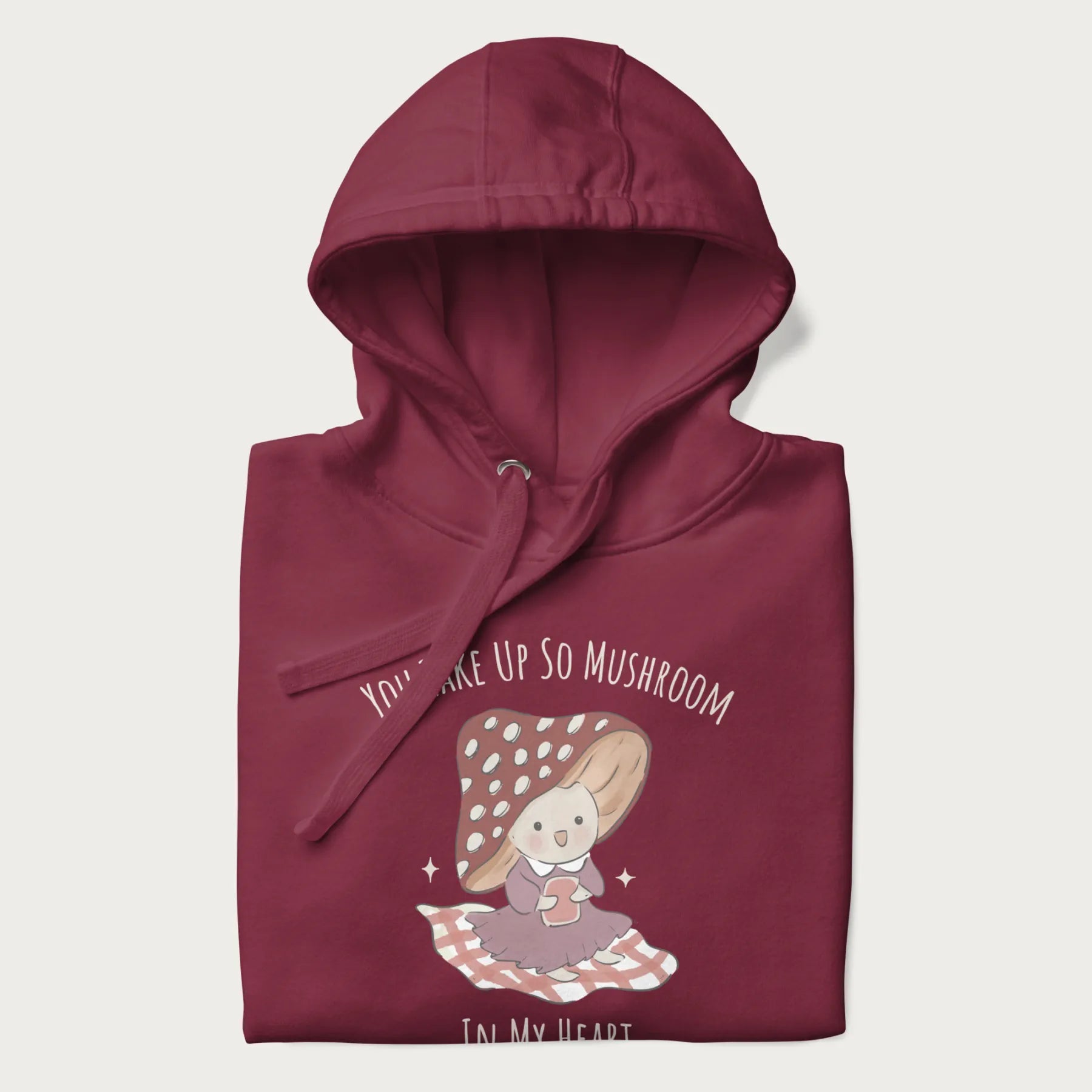 Folded maroon hoodie with a cute mushroom character and the text 'You Take Up So Mushroom in My Heart'.