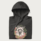 Folded dark grey hoodie with graphic of an adorable raccoon surrounded by mushrooms, foliage, and a crescent moon with stars in the background.