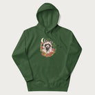 Forest green hoodie with graphic of an adorable raccoon surrounded by mushrooms, foliage, and a crescent moon with stars in the background.