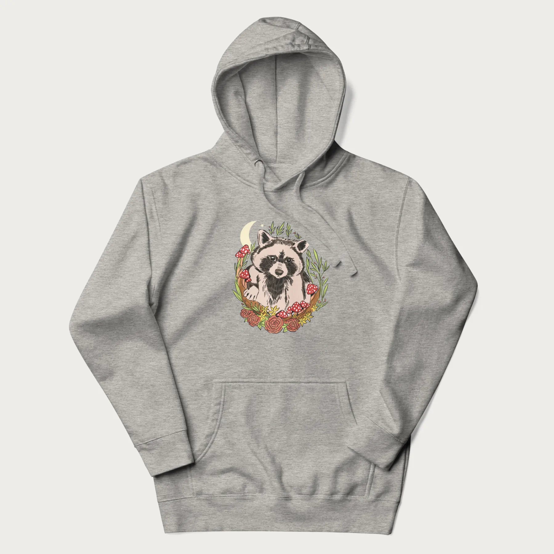 Light grey hoodie with graphic of an adorable raccoon surrounded by mushrooms, foliage, and a crescent moon with stars in the background.