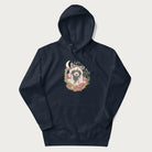 Navy blue hoodie with graphic of an adorable raccoon surrounded by mushrooms, foliage, and a crescent moon with stars in the background.