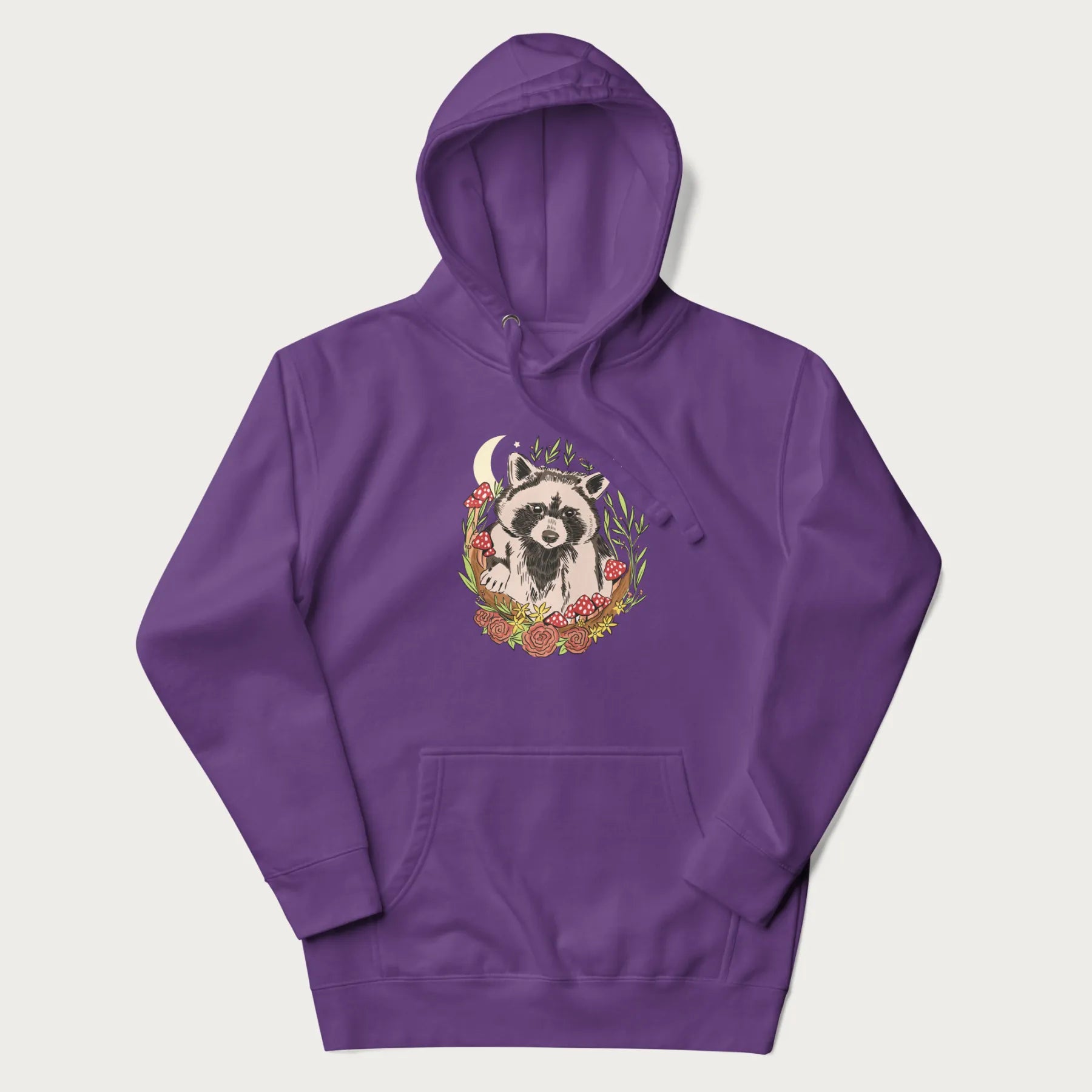 Purple hoodie with graphic of an adorable raccoon surrounded by mushrooms, foliage, and a crescent moon with stars in the background.