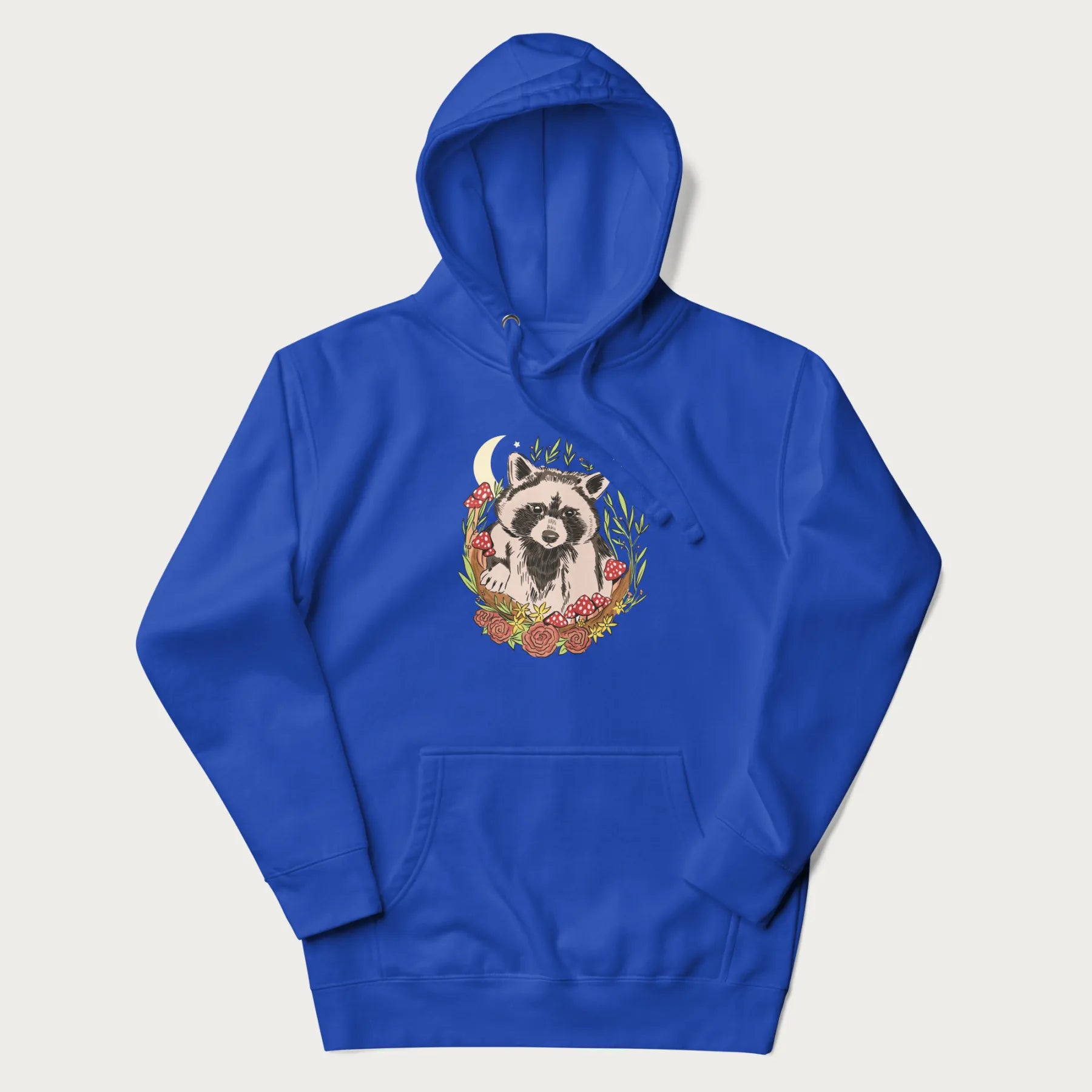 Royal blue hoodie with graphic of an adorable raccoon surrounded by mushrooms, foliage, and a crescent moon with stars in the background.