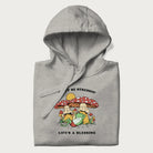 Folded light grey hoodie with a graphic of a frog lounging under mushrooms and the phrases 'Don't Be Stressin' Life's a Blessing'.