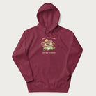 Maroon hoodie with a graphic of a frog lounging under mushrooms and the phrases 'Don't Be Stressin' Life's a Blessing'.