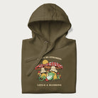 Folded military green hoodie with a graphic of a frog lounging under mushrooms and the phrases 'Don't Be Stressin' Life's a Blessing'.
