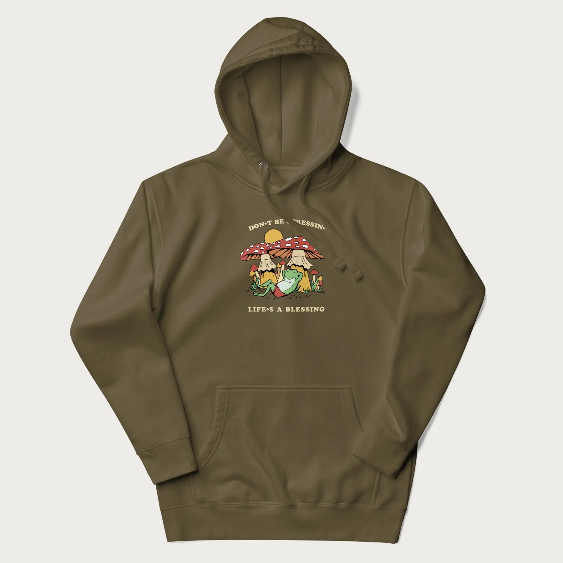 Military green hoodie with a graphic of a frog lounging under mushrooms and the phrases 'Don't Be Stressin' Life's a Blessing'.