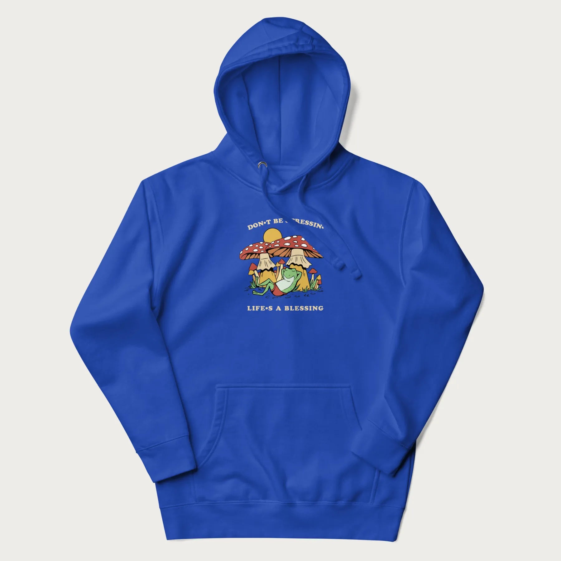 Royal blue hoodie with a graphic of a frog lounging under mushrooms and the phrases 'Don't Be Stressin' Life's a Blessing'.