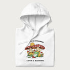 Folded white hoodie with a graphic of a frog lounging under mushrooms and the phrases 'Don't Be Stressin' Life's a Blessing'.