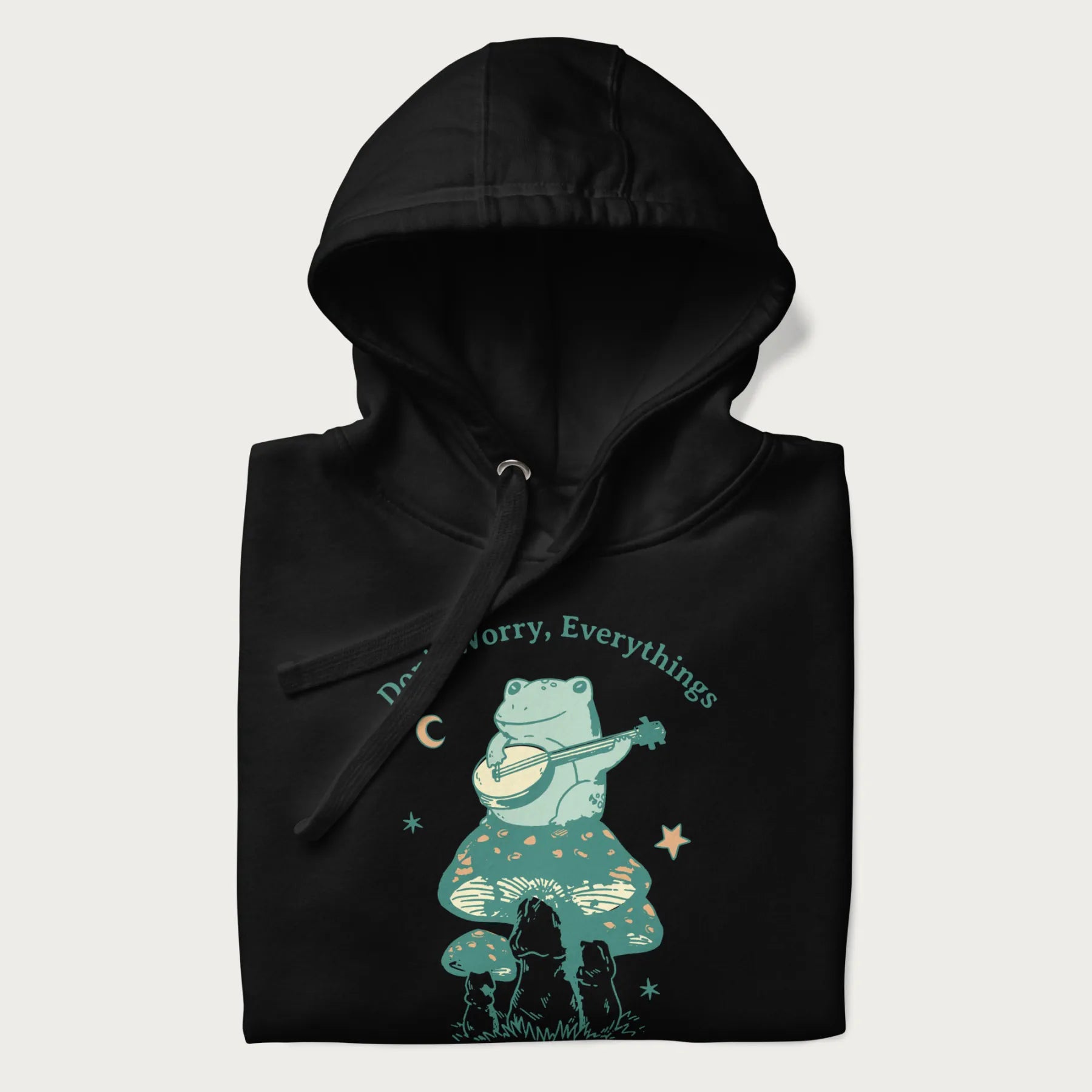 Folded black hoodie with a graphic of a frog playing a banjo on a mushroom under the moon and stars, with the text 'Don't Worry, Everything's Gonna Be Just Fine.'