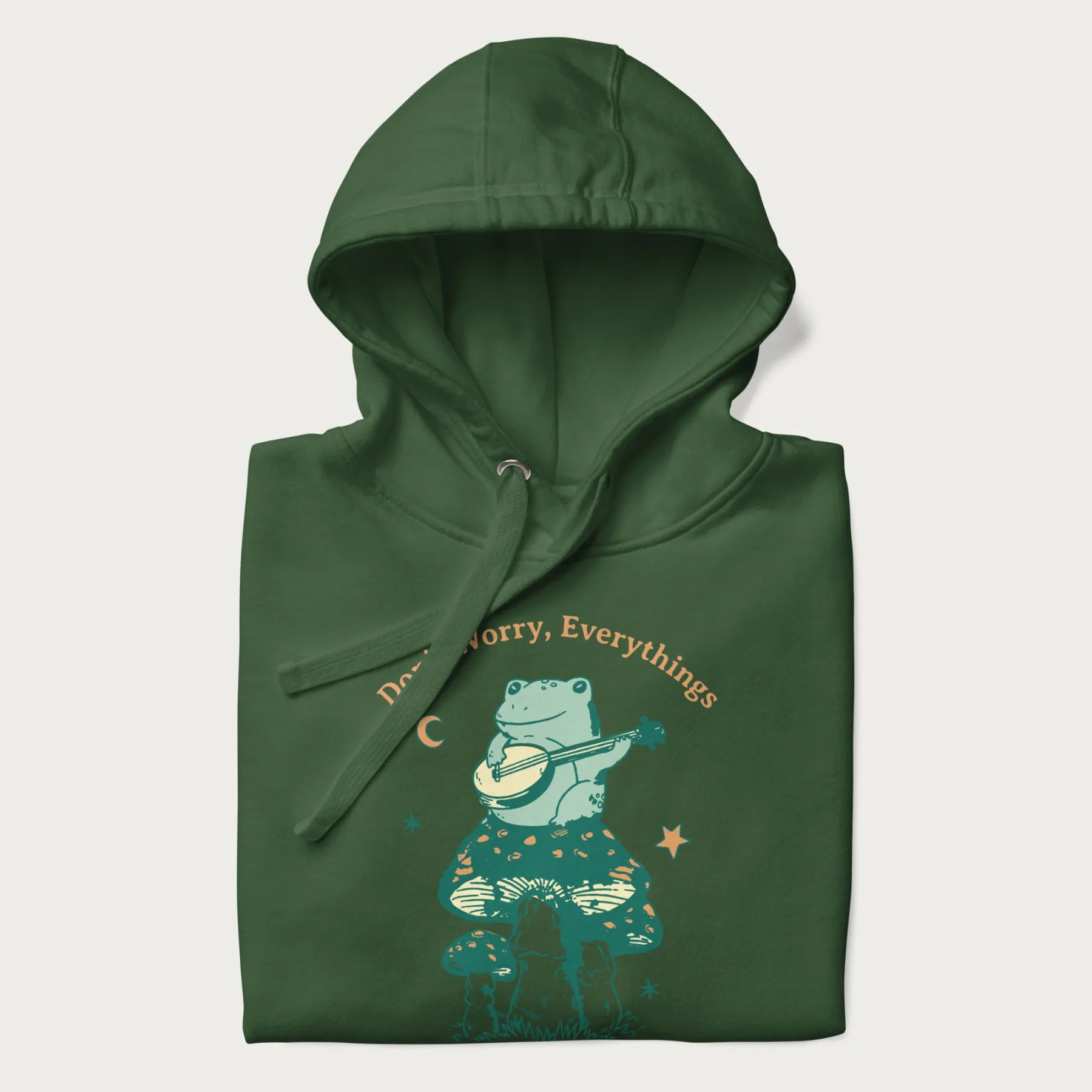 Folded forest green hoodie with a graphic of a frog playing a banjo on a mushroom under the moon and stars, with the text 'Don't Worry, Everything's Gonna Be Just Fine.'