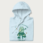 Folded light blue hoodie with a graphic of a frog playing a banjo on a mushroom under the moon and stars, with the text 'Don't Worry, Everything's Gonna Be Just Fine.'