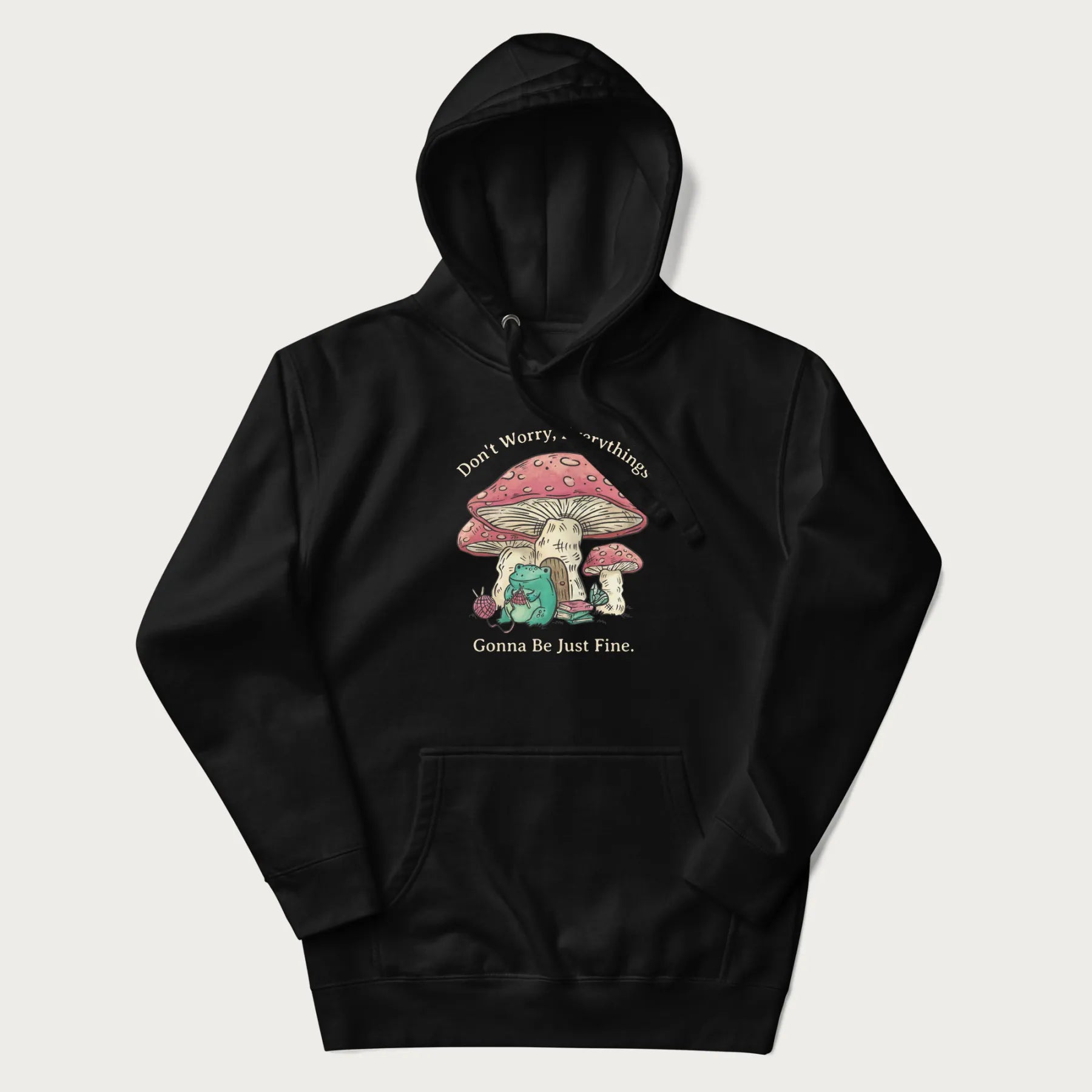 Black hoodie with a graphic of a frog knitting under a large mushroom with the text 'Don't Worry, Everything's Gonna Be Just Fine'.