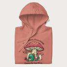 Folded light pink hoodie with a graphic of a frog knitting under a large mushroom with the text 'Don't Worry, Everything's Gonna Be Just Fine'.