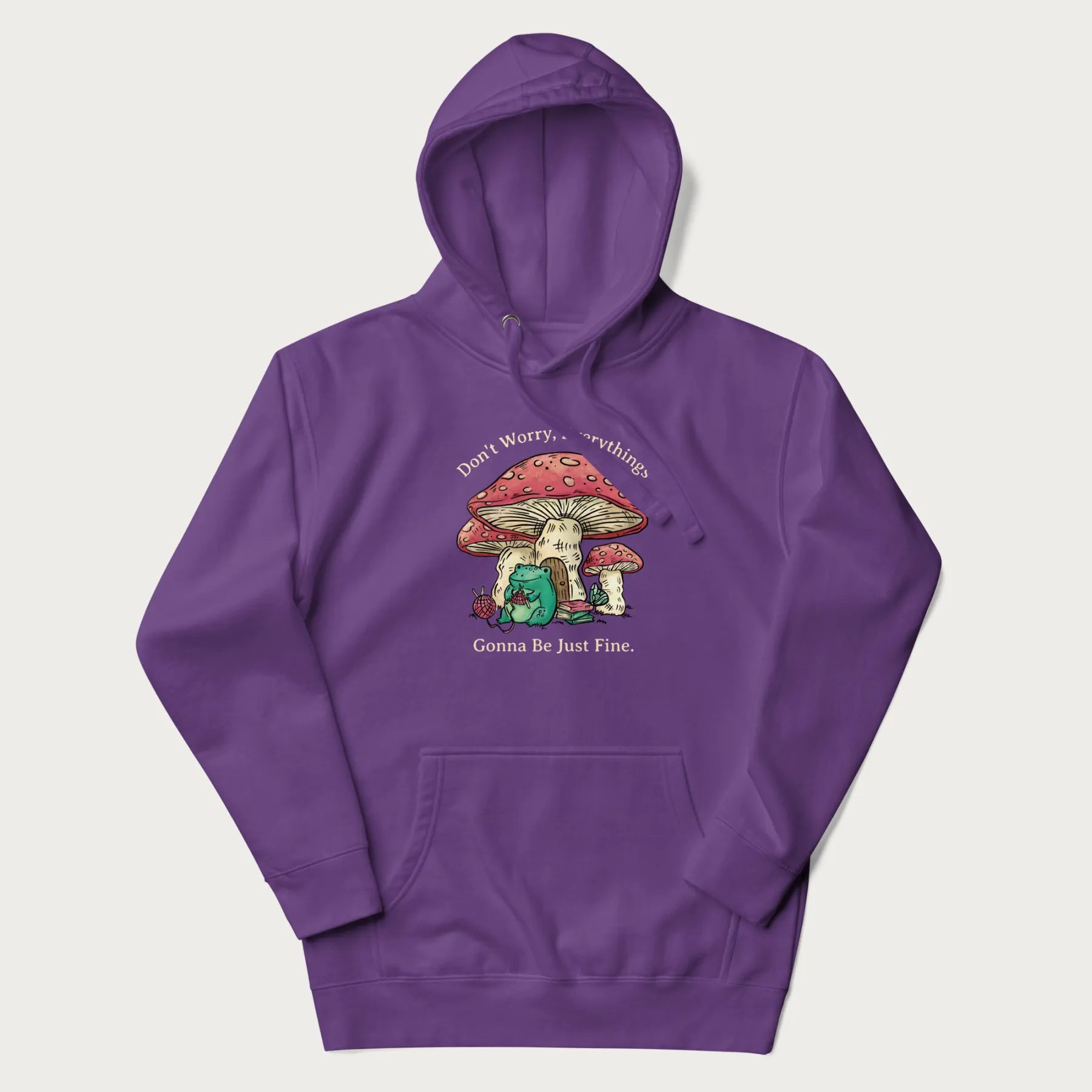 Purple hoodie with a graphic of a frog knitting under a large mushroom with the text 'Don't Worry, Everything's Gonna Be Just Fine'.