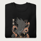 Folded black sweatshirt with Japanese text and a graphic of an eagle and a snake in combat.