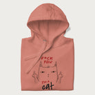 Folded light pink hoodie with a graphic of a cat raising its middle fingers, with the phrase "F*ck You, I'm a Cat" in red text.