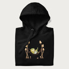 Folded black hoodie with a graphic of a frog lounging in a hammock between tall mushrooms.