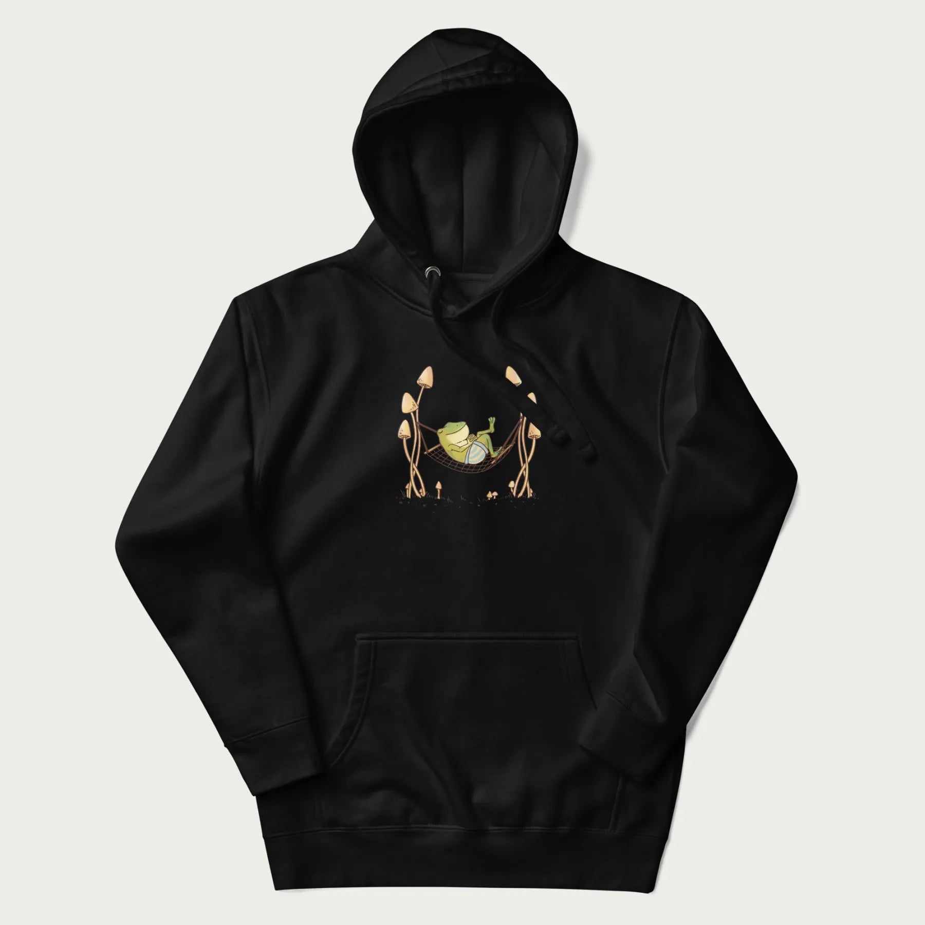 Black hoodie with a graphic of a frog lounging in a hammock between tall mushrooms.
