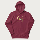 Maroon hoodie with a graphic of a frog lounging in a hammock between tall mushrooms.