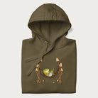 Folded military green hoodie with a graphic of a frog lounging in a hammock between tall mushrooms.