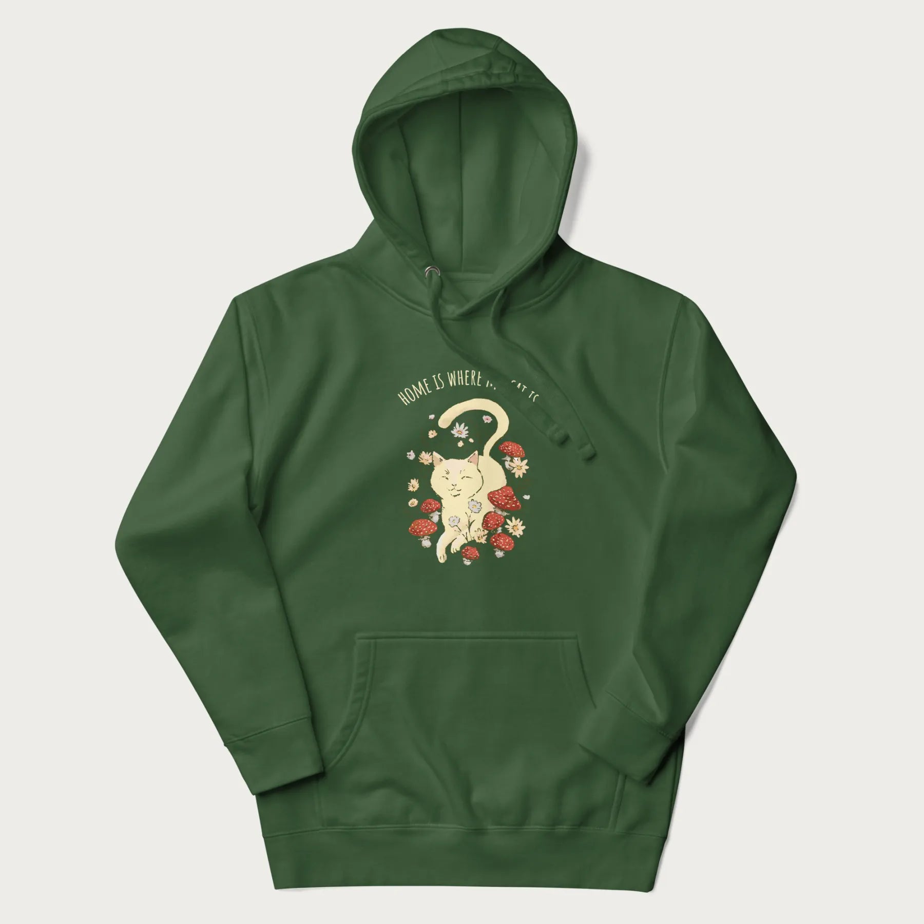 Forest green hoodie with a graphic of a cat nestled among flowers and mushrooms with the text 'Home is Where My Cat Is' above.