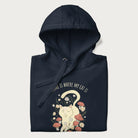 Folded navy blue hoodie with a graphic of a cat nestled among flowers and mushrooms with the text 'Home is Where My Cat Is' above.