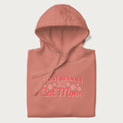 Graphic on a folded light pink hoodie saying 'I Just Wanna Be a Cat Mom' with pink lettering and paw prints.