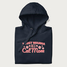 Graphic on a folded navy blue hoodie saying 'I Just Wanna Be a Cat Mom' with pink lettering and paw prints.