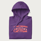 Graphic on a folded purple hoodie saying 'I Just Wanna Be a Cat Mom' with pink lettering and paw prints.