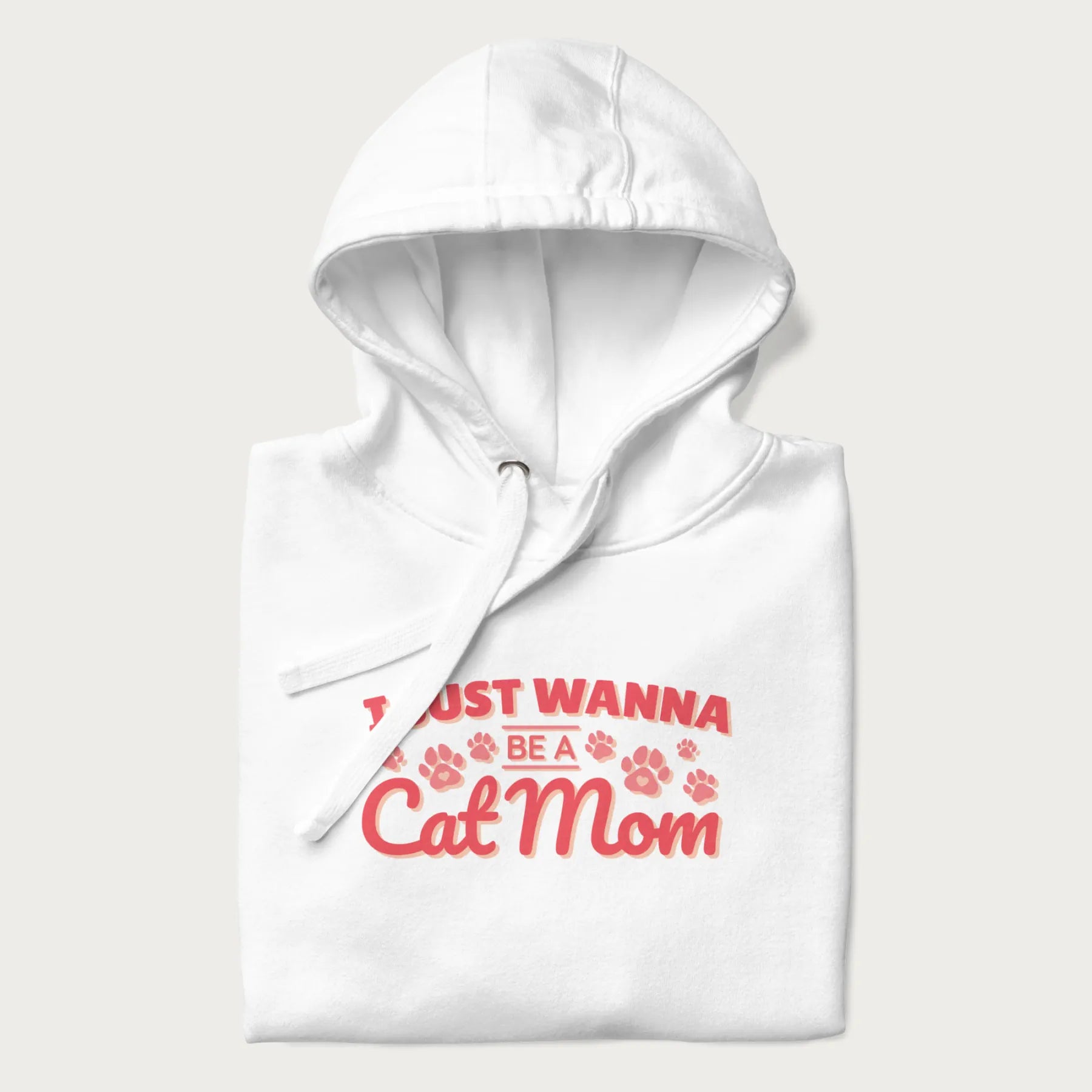 Graphic on a folded white hoodie saying 'I Just Wanna Be a Cat Mom' with pink lettering and paw prints.