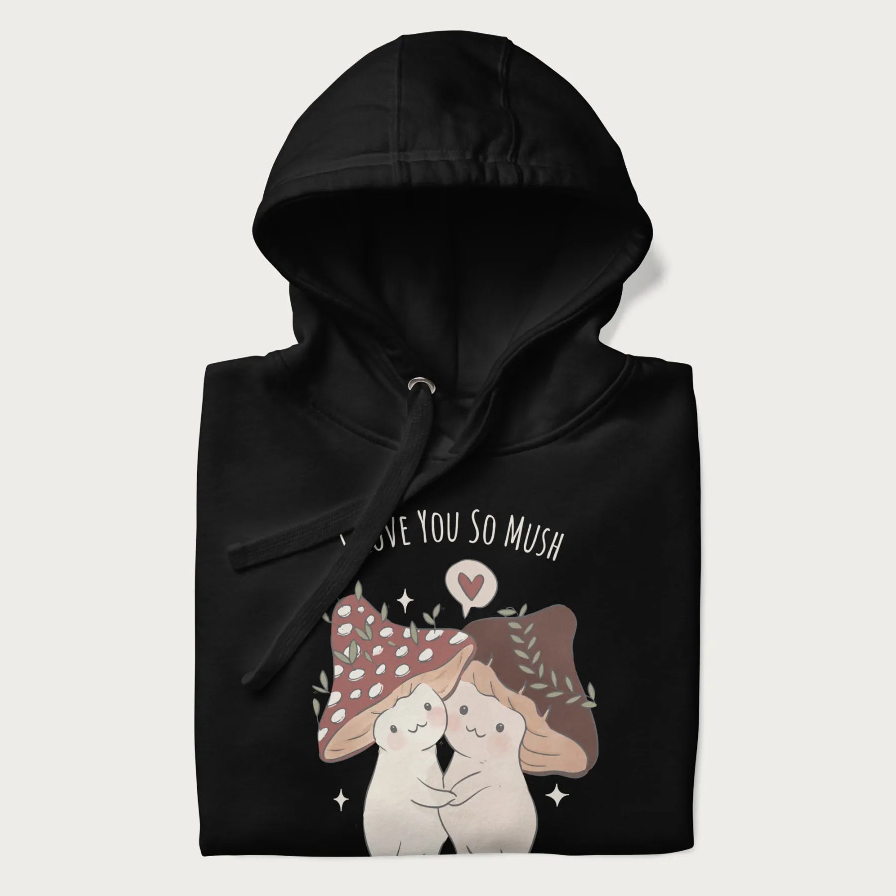 Folded black hoodie with a cottagecore graphic of two cute mushrooms hugging and the text 'I Love You So Mush' above them.