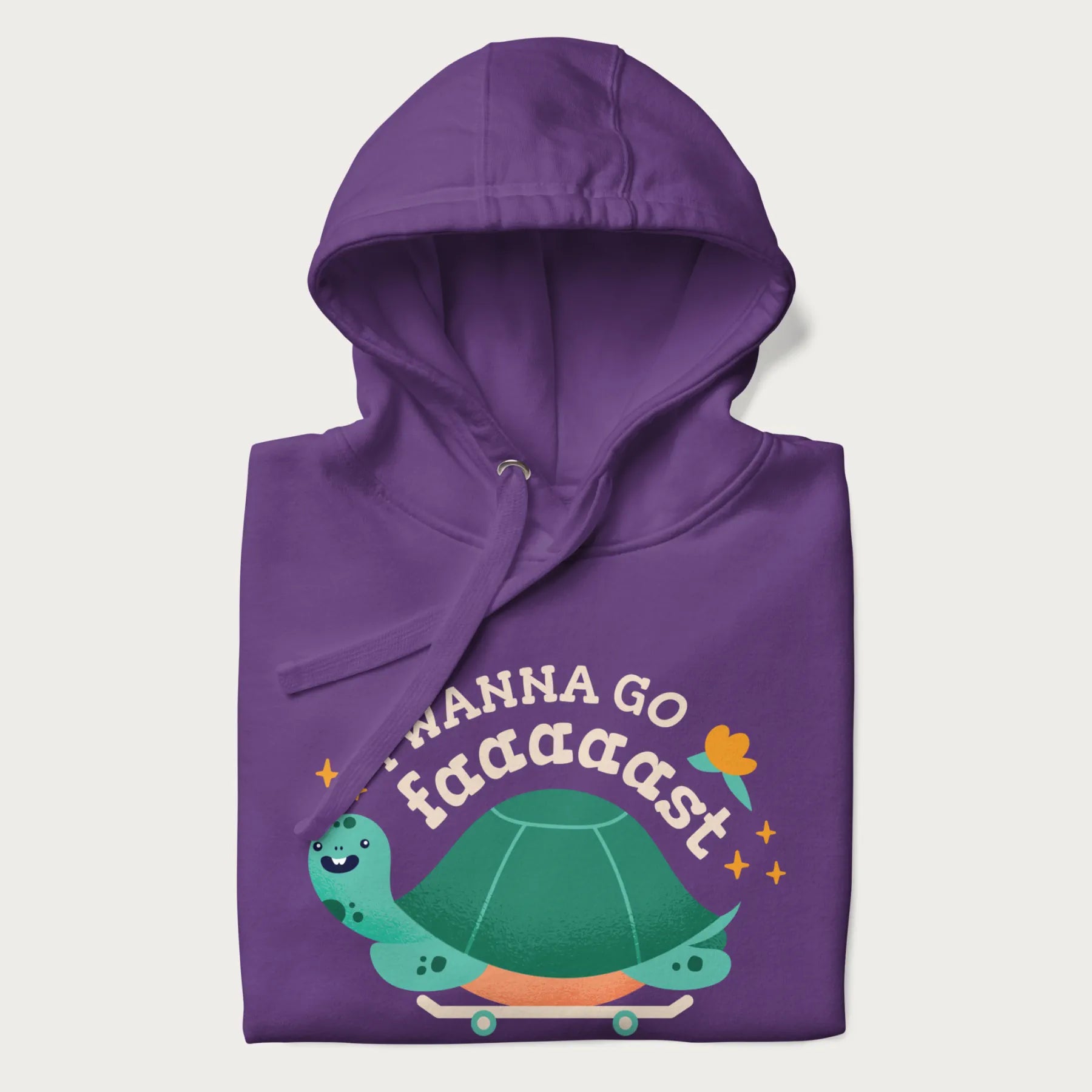 Folded purple hoodie with a graphic of a happy turtle on a skateboard and the text 'I Wanna Go Faaaaast'.