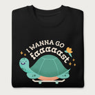 Folded black sweatshirt with a graphic of a turtle on a skateboard and the phrase 'I Wanna Go Fast.'