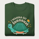 Folded forest green sweatshirt with a graphic of a turtle on a skateboard and the phrase 'I Wanna Go Fast.'