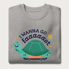 Folded light grey sweatshirt with a graphic of a turtle on a skateboard and the phrase 'I Wanna Go Fast.'