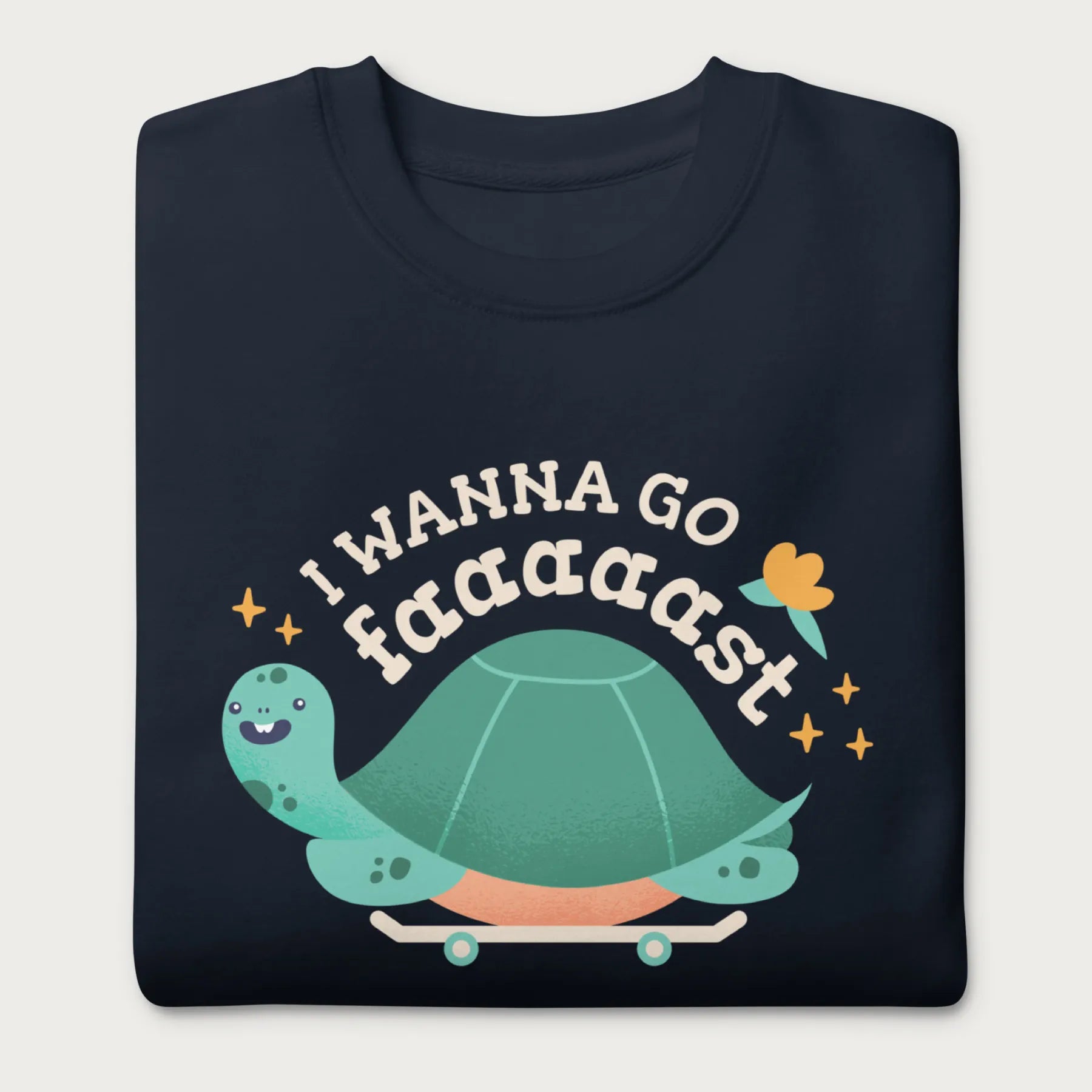 Folded navy blue sweatshirt with a graphic of a turtle on a skateboard and the phrase 'I Wanna Go Fast.'