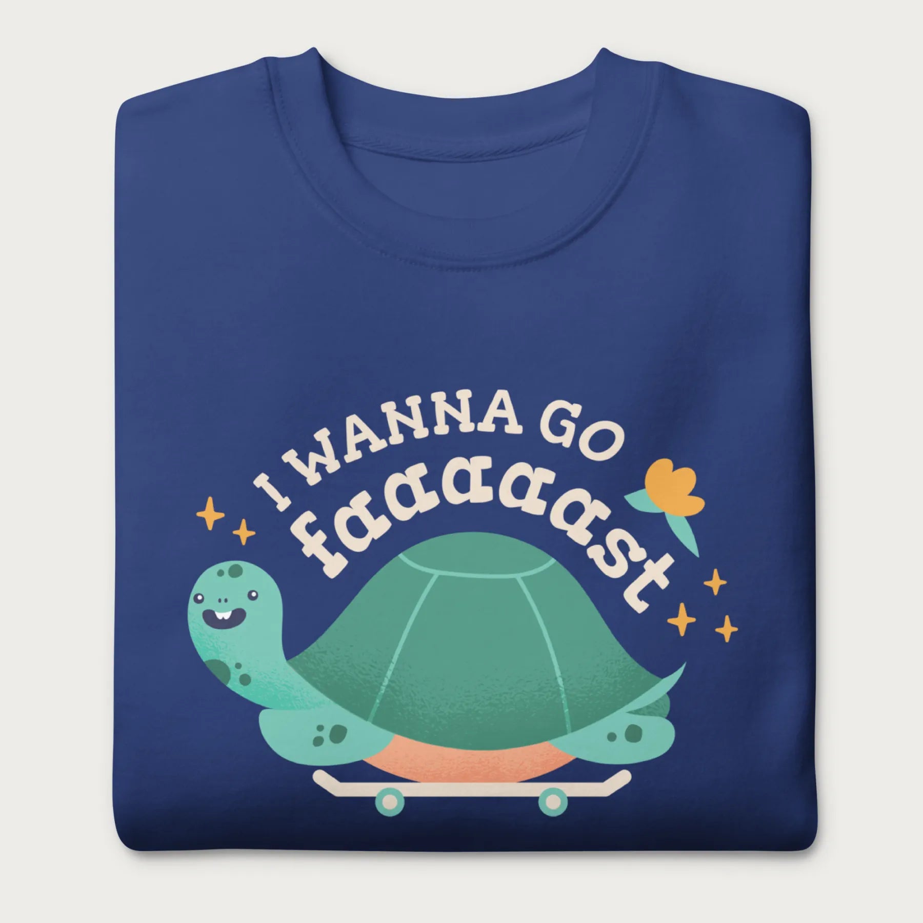 Folded royal blue sweatshirt with a graphic of a turtle on a skateboard and the phrase 'I Wanna Go Fast.'