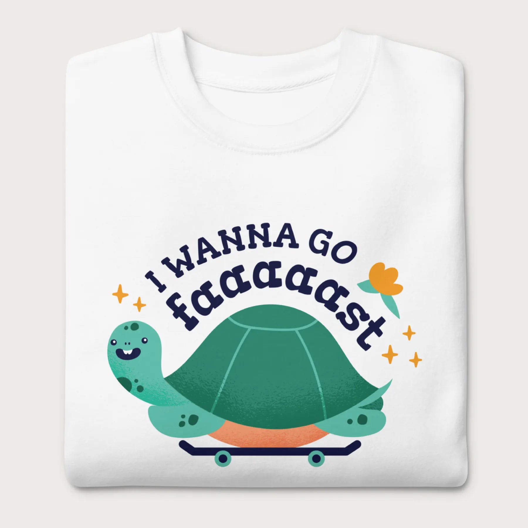 Folded white sweatshirt with a graphic of a turtle on a skateboard and the phrase 'I Wanna Go Fast.'