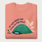 Folded light pink sweatshirt with a graphic of a turtle hiding in its shell and the phrase 'If You Need Me, I'll Be in My Shell.'