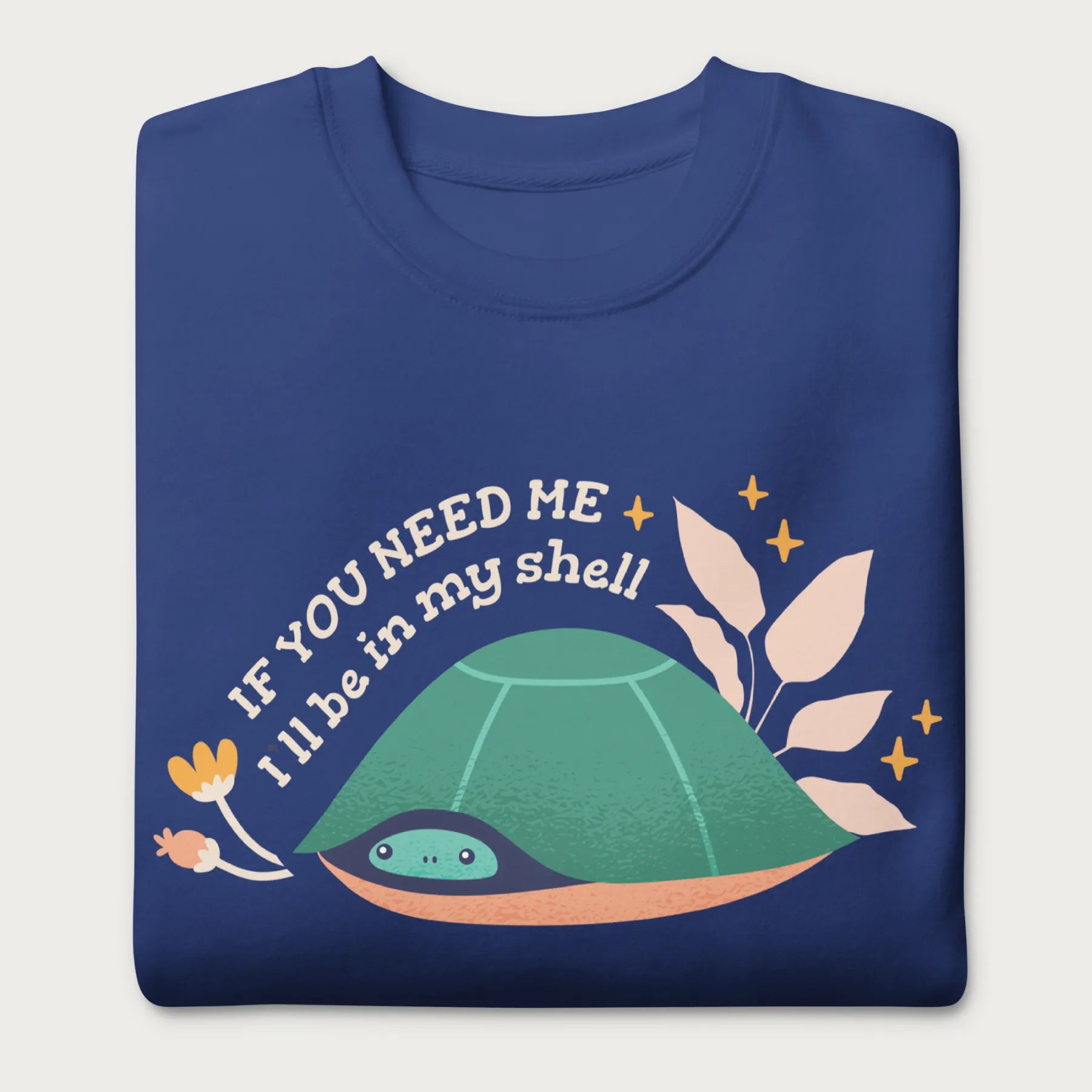 Folded royal blue sweatshirt with a graphic of a turtle hiding in its shell and the phrase 'If You Need Me, I'll Be in My Shell.'