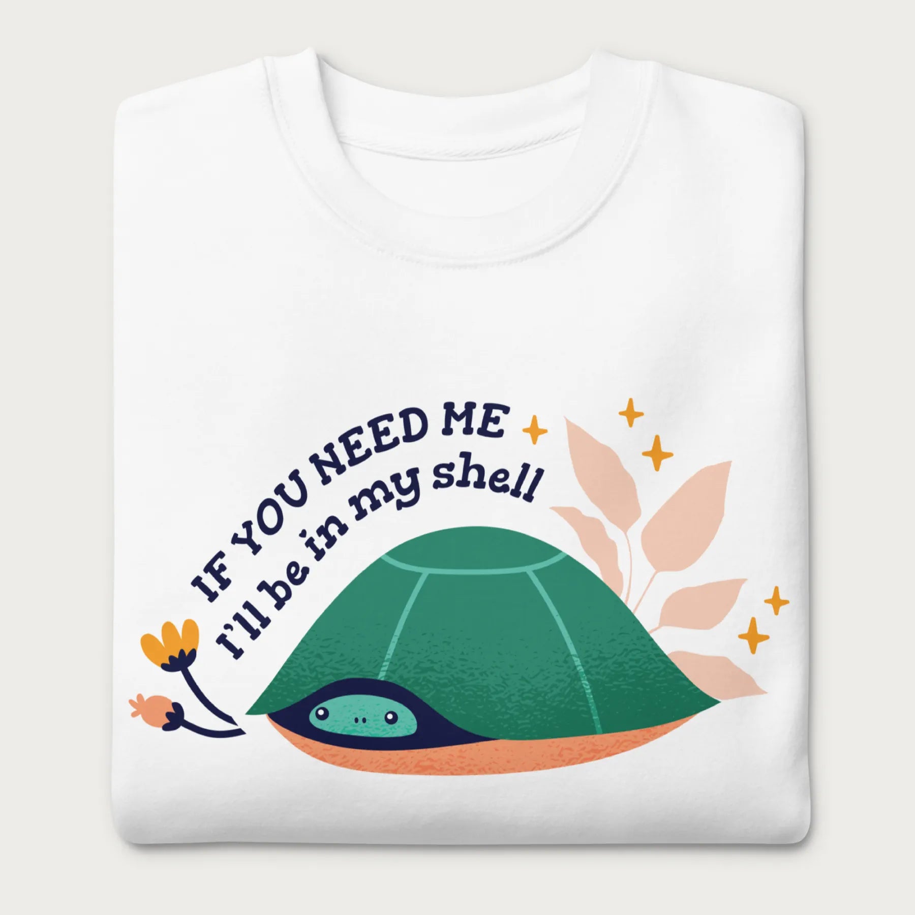 Folded white sweatshirt with a graphic of a turtle hiding in its shell and the phrase 'If You Need Me, I'll Be in My Shell.'