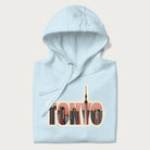 Folded light blue hoodie with graphic of Tokyo's skyline integrated into the word 'TOKYO' in sunset colors.