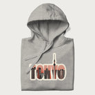 Folded light grey hoodie with graphic of Tokyo's skyline integrated into the word 'TOKYO' in sunset colors.