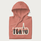 Folded light pink hoodie with graphic of Tokyo's skyline integrated into the word 'TOKYO' in sunset colors.