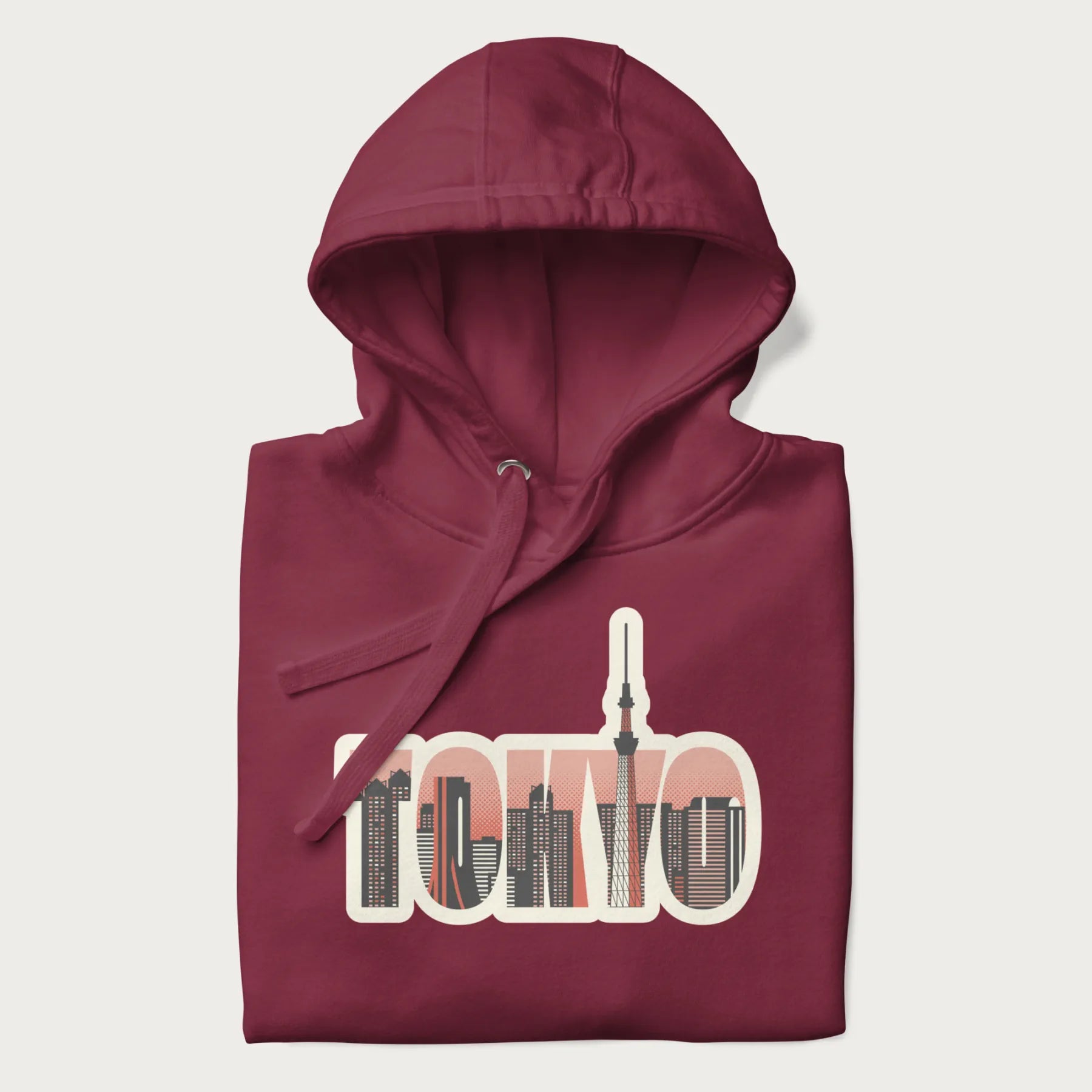 Folded maroon hoodie with graphic of Tokyo's skyline integrated into the word 'TOKYO' in sunset colors.