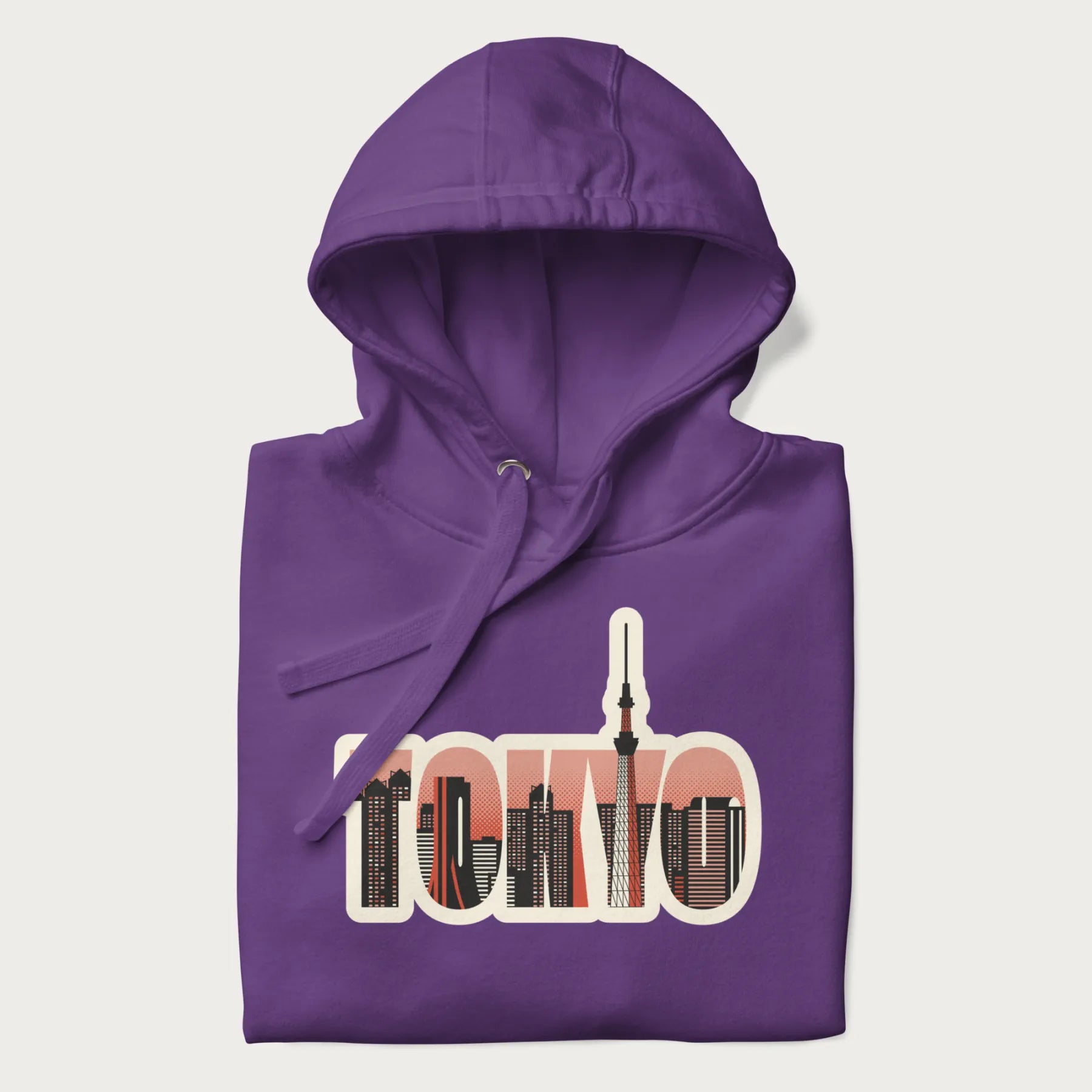 Folded purple hoodie with graphic of Tokyo's skyline integrated into the word 'TOKYO' in sunset colors.