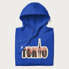 Folded royal blue hoodie with graphic of Tokyo's skyline integrated into the word 'TOKYO' in sunset colors.